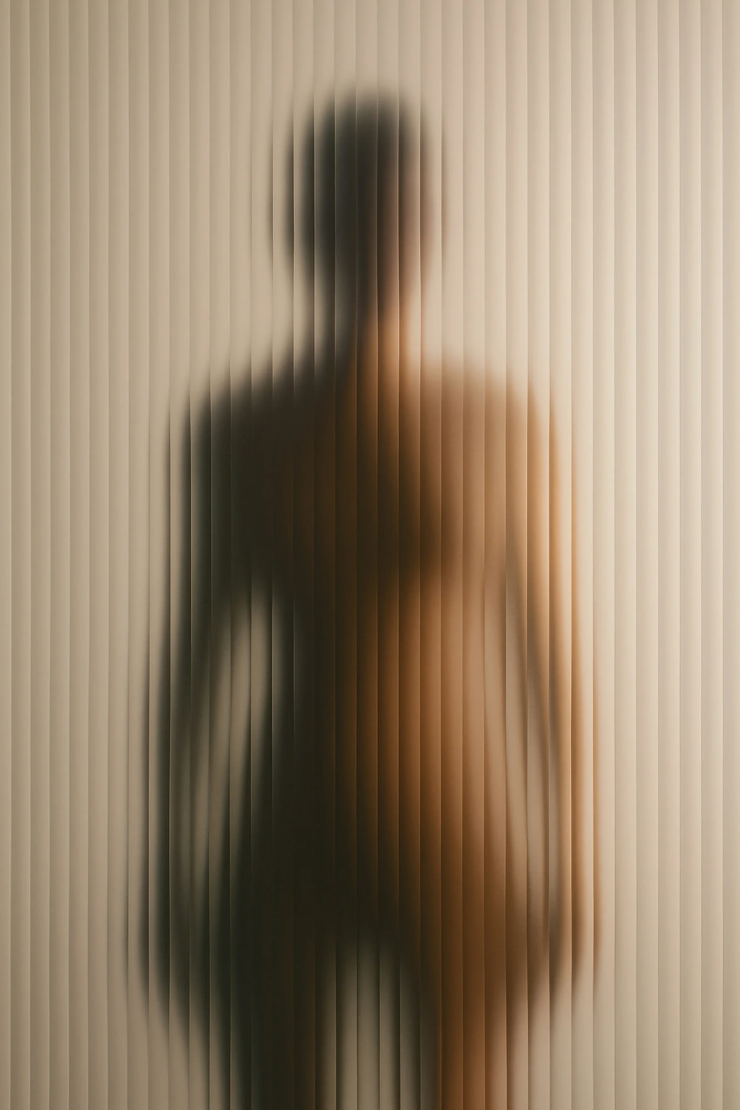 A human silhouette blurred behind fluted textured glass — the living body readable only as an obscured form, its state hidden by the interface through which we look.