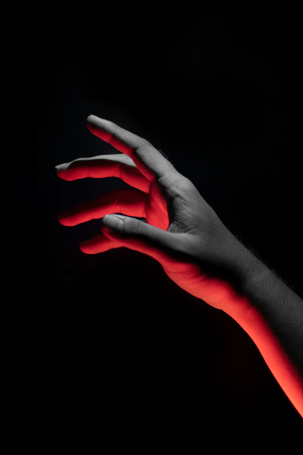 A human hand reaching outward against a dark background, suggesting the physical body as the one interface that cannot be virtualized.